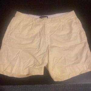 Beige shorts från Stockh lm, stl 38 - Snygga beiga shorts från Stockh lm i klassisk modell med fickor fram och bak, hällor för bälte och uppvikta benslut. Perfekta för varma dagar och lätta att matcha med allt. Sköna och stilrena shorts för dig som gillar enkel och clean look.