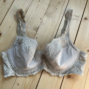 Beige spets-bh från XLNT 85C - Snygg beige bh från XLNT med vackra spetsdetaljer längs kupor och axelband. Bh:n har en klassisk form med breda axelband och mjuk spets som ger en romantisk vibe. Perfekt för dig som gillar feminina detaljer och bekväm passform.