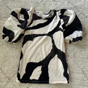 Svartvit topp med puffärmar - Cool topp/blus i svart och vit med stora  mönster och puffiga korta ärmar! Älskar!! Men kommer inte till användning 🥹💕