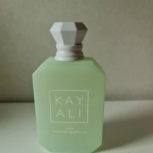 Kayali Yum Pistachio Gelato 100ml OBS LÄS - Kayali Yum Pistachio Gelato 33 är en parfym i en matt ljusgrön glasflaska med vit, diamantformad kork. Doften har noter av pistageglass, hasselnöt, söt rom, vispad grädde, marshmallow och sockervadd.  Den är använd fåtal gånger MEN jag har fått den i present och har ej kvitto, därav säljer jag den så billigt då jag inte kan garantera att den är äkta. Är ingen kayali expert. Se mängd på första bilden. Köp på egen risk då jag varit ärlig med det jag vet - exakt som på bilderna. Utan förpackning