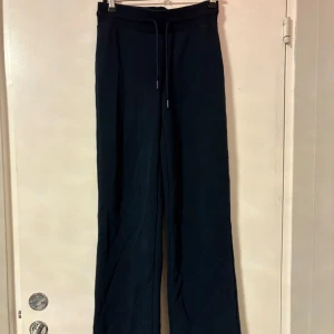 Svarta wide byxor från 157, XS - Svarta byxor från 157 i storlek XS. De har en relaxed bootcut/flared vanlig midja och dragsko i midjan för extra komfort. Perfekta för en chill och stilren look. Materialet känns mjukt och skönt mot huden.