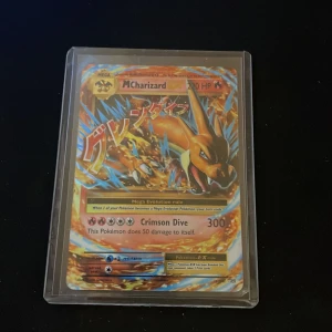 MCharizard EX - Värde 300kr+. Coolt samlarkort med Mega Charizard EX från Pokémon! Perfekt för dig som älskar Pokémon och vill ha en kraftfull och snygg kort i din samling. Kortet är i skyddsplast och har en färgstark design som sticker ut. Ett måste för fans och samlare!
