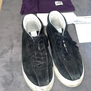 Svarta sneakers från Eytys i mocka - Säljer ett par svarta sneakers från Eytys med ovandel i mocka och vit sula. Skorna har lila detalj på hälen, snörning och vit insida. Klassisk och stilren modell som har utgått och inte går att få tag i längre som passar till många outfits. Nypris 2100kr 