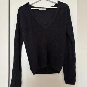 Svart stickad v-ringad tröja NA-KD - Svart stickad tröja från NA-KD i storlek XXS. Tröjan har en djup v-ringning och långa ärmar, perfekt för lager-på-lager. Enkel och stilren design som funkar till många outfits.