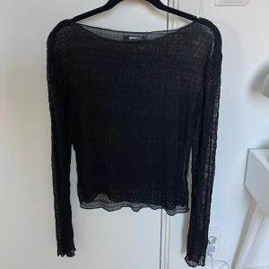 Svart meshblus från Gina Tricot - Säljer en svart transparent meshblus från Gina Tricot i storlek S. Blusen har lång ärm, lätt rynkad struktur och vågig kant nertill och vid ärmslut. Perfekt att styla lager på lager eller med ett snyggt linne under.