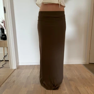 Brun/grön långkjol i mjukt material - Säljer en brun/grön långkjol med rak passform. Kjolen är enkel och stilren utan mönster. Modellen är ca 160cm lång. 