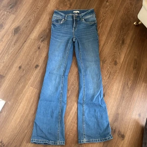 Blå bootcut jeans  - Snygga blå jeans med bootcut passform och klassiska fem fickor. Jeansen gick sönder i fickan så har sytt ihop den. Perfekta för dig som gillar en avslappnad men trendig look.