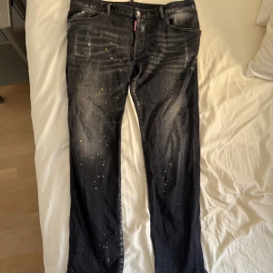 Äkta Dsquared2 ICON jeans Zlatan edition  - Snygga svarta jeans från Dsquared2 ICON med coola vita och gula färgstänk över hela byxorna. Klassisk femficksmodell med raka ben och diskret slitning. Jeansen har en tydlig ICON-lapp bak och är tillverkade i bomull med en skön passform. (AI är för skön)