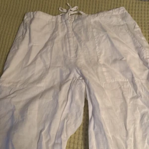 Vita linnebyxor från H&M med snörning - Luftiga vita linnebyxor från H&M i storlek 36-38. Byxorna har snörning och dragkedja i midjan samt raka ben. Perfekta för varma dagar när du vill ha en chill och stilren look.