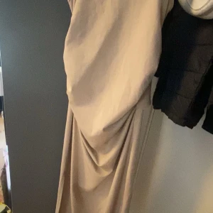 Beige långklänning med knutdetalj - Supersnygg beige långklänning med smala axelband och öppen rygg har även slits på ena sidan vid benet storlek xs (pris kan diskuteras)