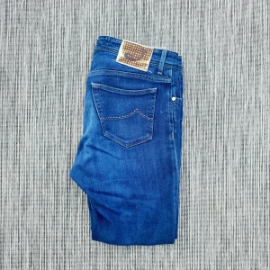 Jacob Cohen  - Snygga blå jeans med klassisk femficksdesign och en cool etikett med nitar på bakfickan. Jeansen har kontrastsömmar och är tillverkade i slitstarkt denim. Perfekta för dig som gillar en tidlös och avslappnad stil.!AI BESKRVINING! Om ni vill ha fler bilder eller om ni har andra funderingar och frågor skriv.