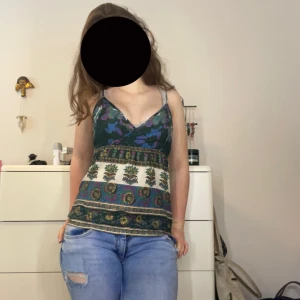 Blommig mönstrad linnetopp från Topshop - Supersöt linnetopp från Topshop med blommigt mönster i grönt, blått, lila, gult och vitt. Toppen har smala axelband med knyt och små pärldetaljer, omlott vid bysten och v-ringning. Toppen har en dragkedja på baksidan. ❤️❤️