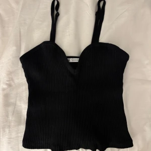 Svart ribbad korsett-topp Zara - Snygg svart korsett-topp med ribbad struktur och justerbara smala axelband. Använd 1 gång 