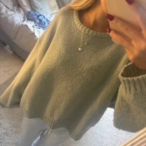 Ljusgrön oversized stickad tröja - Supermysig ljusgrön stickad tröja med oversized passform och breda ärmar. Tröjan har rund halsringning och ribbade muddar vid ärmslut och nederkant. 