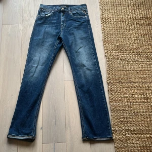 Blå raka jeans från Replay - Snygga blå jeans från Replay med klassisk femficksdesign och raka ben. Jeansen har en mellanblå tvätt med lätt slitning och tydliga sömmar. Märkespatch bak i midjan och diskret Replay-logga vid fickan. Storleken är W30 L30 Jeansen är inprimsip oanvända så hör av er om ni är intresserade eller har tankar om något👍
