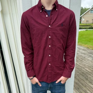 Vinröd Ralph Lauren skjorta - En riktigt fet vinröd ralph lauren skjorta riktig stilig passform och skön. Storlek S slim fit grabben på bilden är 185 cm 70kg. hör gärna av er vid funderingar mvh AeCloset💯