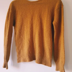 Omlott kofta i orange / senapsgul från NA-KD - Mysig brun omlott kofta från NA-KD i stickat material. Koftan har lång ärm, ribbade muddar och en snygg omlottfront som ger en avslappnad men trendig look. Perfekt att slänga på sig när det är kyligt ute.  Helt skick dock noppror