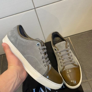 Lanvin skor  - Snygga grå sneakers från Lanvin med glansig brun tåhätta och snörning. Skorna har en stilren design med en kombination av mocka och skinn. Storlek 43. Skorna är i topp skick nästan som nya. Priset är förhandlingsbart vid en snabb affär:)