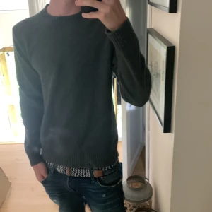 Mörkgrå stickad tröja Samsøe Samsøe - Mörkgrå stickad tröja från Samsøe Samsøe med rund halsringning och ribbade muddar. Enkel och stilren modell som passar perfekt till jeans. Långärmad och i mjukt material som känns skönt mot huden.