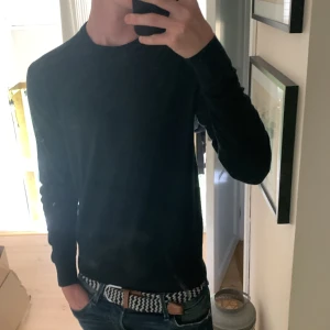 Grön stickad tröja från Uniqlo - En stilren svart stickad tröja från Uniqlo i storlek S. Tröjan har rund halsringning och långa ärmar, perfekt för lager-på-lager eller som den är. Enkel och clean look som funkar till jeans eller chinos.