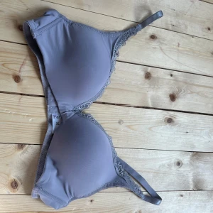 Grå bh-topp med spets från F&F - Snygg grå bh-topp från F&F i storlek XL. Toppen har släta kupor och tunna axelband samt fina spetsdetaljer längs kanterna. Perfekt för dig som gillar en enkel men ändå feminin look.