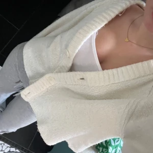 Vit kofta  - Supermysig vit kofta med croppad passform och bred ribbad v-ringning. Tröjan har stora knappar framtill och långa ärmar. Perfekt att slänga över ett linne eller t-shirt för en chill och stilren look💗