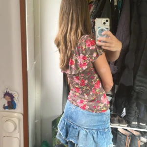 Blommig brun topp i S - Supersöt brun topp från H&M med blommigt mönster i rosa, rött och grönt i storlek S. Modellen har en volangdetalj vid halsringningen och en lätt figurnära passform. Perfekt för en somrig och lite romantiskt känsla.