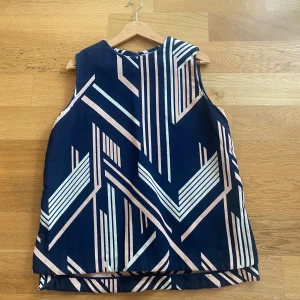 Mönstrade blå byxor med grafiskt tryck - Snygga byxor och bluse i mörkblått med grafiskt mönster i vitt och ljusrosa. Byxorna har raka ben och resår i midjan för en bekväm passform. Perfekta för dig som gillar att sticka ut med coola mönster och färger. Materialet känns mjukt och följsamt.