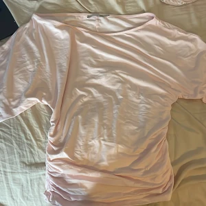 Ljusrosa t-shirt med snörning från 157 - Ljusrosa t-shirt från 157 i storlek L. Oversized fit med korta ärmar och snygg snörningsdetalj på ena sidan. Mjuk och skön i bomull, perfekt för en chill look. Rund halsringning och enkel design som är lätt att matcha.