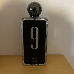 Afnan 9PM Eau de Parfum 100ml - Afnan 9PM Eau de Parfum i en stilren, rektangulär glasflaska med svart etikett och stora vita siffror. Flaskan har en rund, mörkgrå kork och rymmer 100 ml. Doften är känd för sina varma, söta och kryddiga toner – perfekt för dig som gillar unika och moderna parfymer. KÖP ELLER BYT!