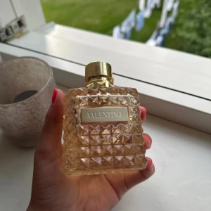 Valentino parfym born in Roma Donna the gold  - Exklusiv parfym från Valentino i en fyrkantig, mönstrad glasflaska med guldiga detaljer och lock. Flaskan har en lyxig känsla med nitar på halsen. Jag säljer den för att den inte kommer till användning, som man kan se på produkten så har ja änvånt ytters lite av parfymen, den är 100 ml och köpt för 1800:)