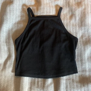 Svart ribbad linnetopp från SHEIN - Säljer en svart ribbad linnetopp från SHEIN med smala axelband och croppad passform. Toppen har en enkel och stilren design som är lätt att matcha med olika outfits. Perfekt för dig som gillar minimalistisk stil.