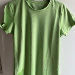 Grön funktions-tshirt från Mammut - •Snygg ljusgrön t-shirt från Mammut i funktionsmaterial, perfekt för träning.  •T-shirten har korta ärmar, rund hals och diskreta Mammut-loggor på ärm och nederkant.  •Materialet är mesh-liknande polyester som andas och känns lätt mot huden. •Sparsamt använd. Mycket bra skick. Tvättad •Djurfritt och rökfritt hem.
