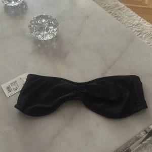 Svart bandeau bikiniöverdel från SOC - Svart bandeau bikiniöverdel från SOC med snygg rynkning framtill och smidig knäppning bak. Finns även knytband till 