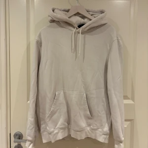 Beige hoodie med huva och ficka - Snygg beige hoodie med huva och dragsko, samt en stor magficka framtill. Tröjan har långa ärmar och ribbade muddar vid ärmslut och nederkant. Perfekt för en chill och avslappnad stil.