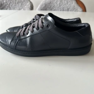 Saint Laurent 01 skor - Stilrena blåa sneakers från Saint Laurent i slätt skinn med rund tå och platt sula. Skorna har blåa snören och diskret logga på plös och häl. Perfekta för dig som gillar minimalistisk och lyxig streetstyle.