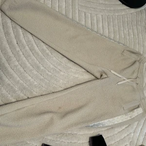 Beige fleecebyxor med snörning - Mysiga beige fleecebyxor med snörning i midjan och en cool detalj längs benet. Perfekta för chill dagar hemma eller när du vill vara extra bekväm. Materialet är mjukt och värmande, och byxorna har en loose passform. Fläcken pp bilden går lätt bort, dom är från lidl och var extremt populära 2022-2023