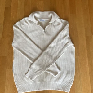 Vit ribbad half zip tröja från Zara - Säljer en vit ribbad tröja från Zara med half zip och hög krage. Tröjan är tillverkad i 100% bomull och har långärmade ärmar. Perfekt för dig som gillar stilrena och enkla plagg med snygg passform.