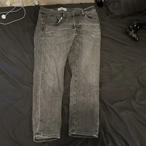 Grå croppade jeans från Jack & Jones - Snygga grå jeans från Jack & Jones med croppad passform. Jeansen har klassisk femficksdesign, raka ben och är tillverkade i bomull. Perfekta för dig som gillar en avslappnad men trendig stil. Storlek 30/30/M. 