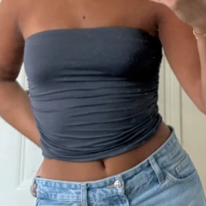 Mörkgrå bandeautopp - Säljer en mörkgrå bandeau tubtopp från Stradivarius, den har rynkor på sidorna som gör den lite mer speciell