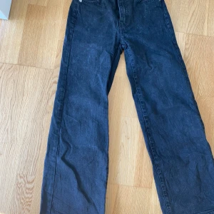 Svarta snygga jeans - Snygga svarta jeans från Lager 157 i rak modell. Jeansen har klassisk femficksdesign, silverfärgade knappar och bälteshällor. Materialet är jeans och färgen är mörk, vilket ger en stilren och enkel look.