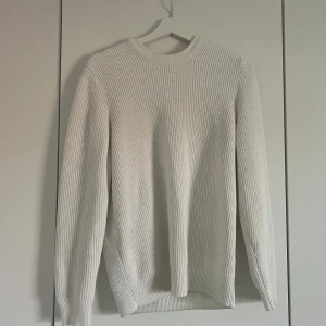 Vit ribbstickad tröja från Zara - Säljer en stilren vit ribbstickad tröja från Zara i storlek M. Tröjan har rund halsringning och långa ärmar, perfekt för lager på lager. Enkel och clean design som passar till allt. Supermjuk och skön att bära.