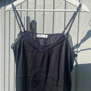 Svart satintopp - Svart linne i satin från Hollister. Storlek M. Justerbara band. 