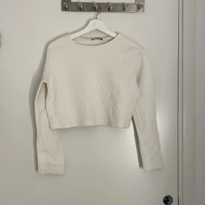 Vit croppad stickad tröja Zara - En stilren vit croppad stickad tröja från Zara med rund halsringning och långa ärmar. Perfekt för lager-på-lager och enkel att matcha med allt möjligt. Tröjan har en ribbad struktur som ger en snygg och modern känsla.