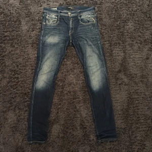 Replay Anbass slim jeans blå, stl 30:32 - Snygga Replay Anbass jeans i mörkblå tvätt med slitningar och ljusa partier framtill. Slim fit-modell med klassiska fem fickor och snygga detaljer på bakfickorna. Tillverkade i stretchig jeans för skön passform. Jeansen sitter mer som 30/32. Kan skicka mer bilder samt mått på jeansen privat om de önskas. 