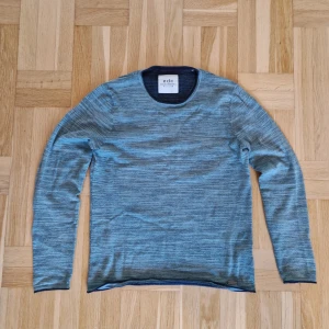 Blåmelerad långärmad tröja EDC - Snygg blåmelerad långärmad tröja från EDC Brand. Tröjan har rund halsringning och diskret metallogo vid nederkanten. Mjuk och tunn stickad känsla, perfekt för lager-på-lager. Passar dig som gillar stilren och enkel design. Storlek M men passar S.