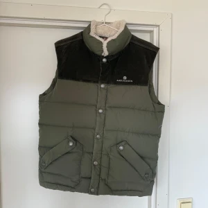 Amundsen Groomer vest - Selger denne pent brukte Amundsen Groomer vesten i fargen Nato (grønn) da jeg har kjøpt en i en annen størrelse. Den er i god stand, men har noen få og veldig lite synlige bruksmerker. En flekk ved siden av ett knappehull (dette kommer under når vesten kneppes igjen), 3 små hull langs kanten innvendig i vesten (veldig små, uten betydning og ikke synlige) og noe slitasje på lommene foran (det som er litt hvitt). Alt er vist på bildene. Grønn selges ikke lenger men nypris er 6299kr 