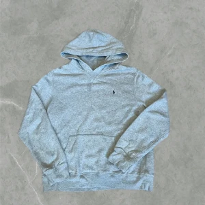 Grå hoodie från Ralph Lauren - Snygg grå hoodie från Polo Ralph Lauren. Klassisk design med huva, känguruficka och broderad logga på bröstet. Det är xl i barn storlek men sitter som en M i herrstorlek. Den är i mycket bra skick