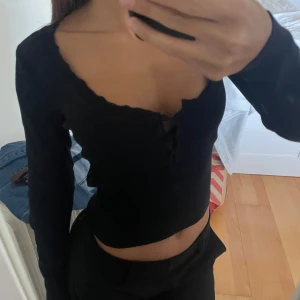 Långärmad topp med knappar - Superfin svart långärmad topp från Zara med urringning. Fint mönster upptill vilket syns på andra bilden!! Knappt använd, bra skick!