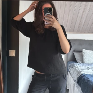 Svart loose blus med vida ärmar - En svart blus med loose passform och trekvartsärmar som är lite puffiga. Enkel och stilren design utan mönster eller detaljer, perfekt att styla med smycken eller lager på lager. Materialet känns mjukt och lätt, troligen bomull eller linne. Tröjan passar för dom som har storlek s/m 